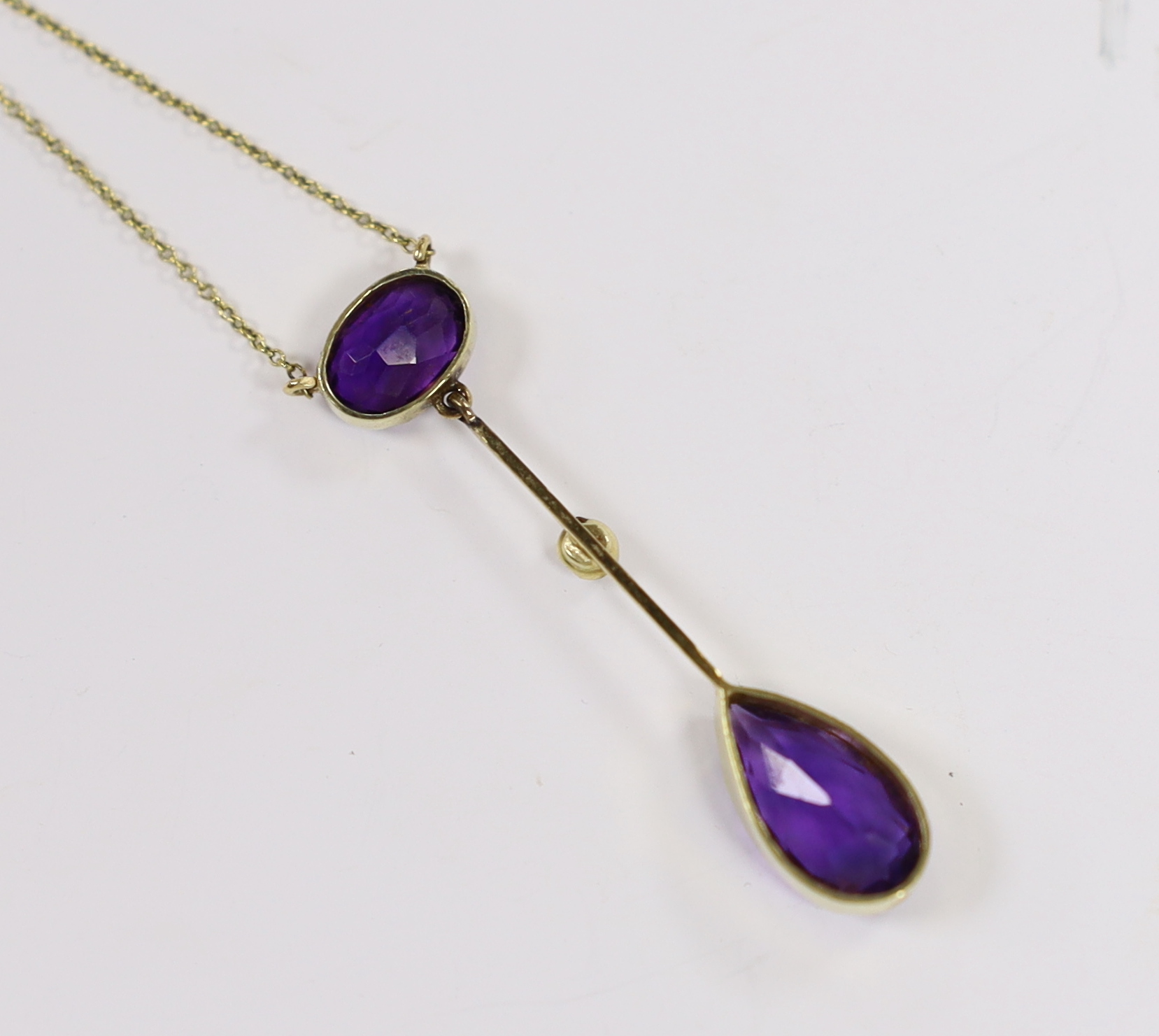 An Edwardian 15ct, two stone amethyst and single stone split peal set drop pendant necklace, overall 39cm (chain knotted), gross weight 3.3 grams.